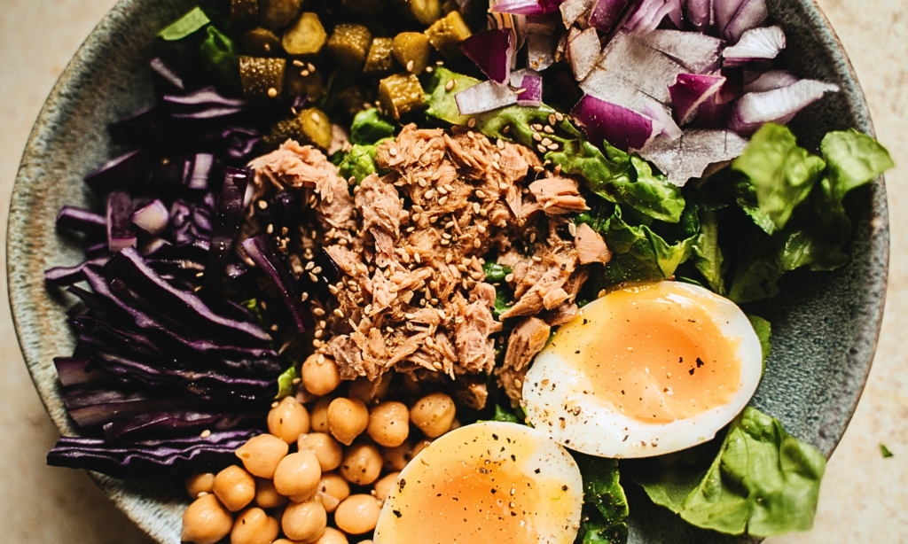 Plate with eggs, tuna, fresh vegetables and chickpeas showing different sources of animal and plant-based protein