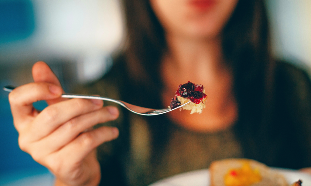 Woman holding a fork with high protein waffle with berries
